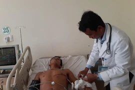 Bác sỹ Ngô Tuấn An, Khoa Ngoại tổng quát, Bệnh viện Bà Rịa, kiểm tra vết mổ cho bệnh nhân Danh Ngộ. (Ảnh: Hoàng Nhị/TTXVN)