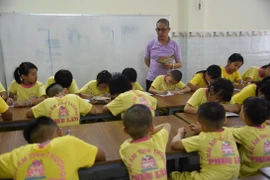 Anh Nguyễn Văn Lâm dạy trẻ học bài ngay tại mái ấm Phúc Lâm. (Ảnh: Công Phong/TTXVN)