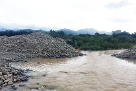 Nhiều đống đá lớn đã được doanh nghiệp khai thác, tập kết đã cản trở dòng chảy của sông Dinh. (Ảnh: Công Thử/TTXVN)