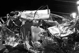 Tại hiện trường, xe du lịch 7 chỗ ngồi bẹp dúm sau vụ va chạm. (Ảnh: TTXVN)