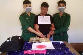 Đối tượng vận chuyển ma túy (ở giữa) cùng tang vật. (Ảnh: TTXVN)