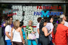 Người dân xếp hàng bên ngoài một siêu thị ở Caracas. (Nguồn: AFP/TTXVN)