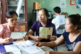 Tuyên truyền cho các hộ gia đình tham gia mua thẻ Bảo hiểm y tế. (Ảnh: Dương Ngọc/TTXVN)