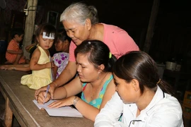 Các em học sinh chăm chú nghe cô giáo giảng bài. (Ảnh: Đậu Tất Thành/Vietnam+)