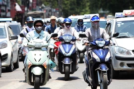 'Kín mít từ đầu tới chân' là phương pháp chống lại cái nắng nóng của người tham gia giao thông trong những ngày này. (Ảnh: Trọng Đạt/TTXVN) 