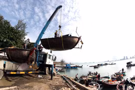 Xe cần cẩu đưa các phương tiện đánh bắt thủy sản của ngư dân Đà Nẵng lên bờ, vận chuyển vào sâu đất liền để tránh bão số 9. (Ảnh: Trần Lê Lâm/TTXVN)