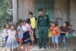 Cán bộ Đồn biên phòng Làng Mô cùng trẻ nhỏ thôn Trung Sơn, xã Trường Sơn, huyện Quảng Ninh (Quảng Bình). (Ảnh: Danh Lam/TTXVN)