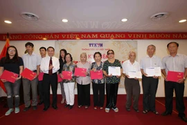 Tổng Giám đốc Thông tấn xã Việt Nam Nguyễn Đức Lợi trao sổ tiết kiệm cho các thân nhân gia đình liệt sỹ. (Ảnh: Quý Trung/TTXVN)