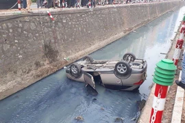 Ôtô lộn ngược và rơi thẳng xuống mương nước phía dưới. (Ảnh: Sơn Bách/Vietnam+)