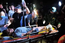 Ngư dân Nguyễn Ngọc được các lực lượng và gia đình hỗ trợ đưa đi bệnh viện cấp cứu, điều trị. (Ảnh: TTXVN phát)