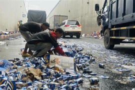 Nhiều người dân hỗ trợ tài xế dọn dẹp các vỏ lon bia bị đổ ở hầm chui ngã tư Vũng Tàu (Biên Hòa, Đồng Nai). (Ảnh: Lê Xuân/TTXVN)