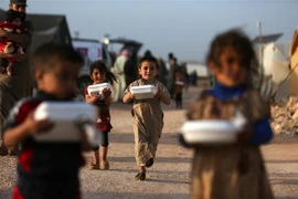 Trẻ em Syria nhận thức ăn cứu trợ tại trại tị nạn ở Dana, tỉnh Idlib. (Ảnh: AFP/TTXVN)