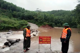 Lực lượng Đồn Biên phòng Ra Mai (huyện Minh Hóa, Quảng Bình) chốt chặn không cho người dân qua các ngầm tràn khi nước lũ dâng cao. (Ảnh: TTXVN phát)