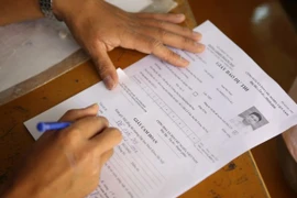 Thí sinh viết giấy cam đoan để sửa chữa thông tin. (Ảnh: Lê Minh Sơn/Vietnam+)