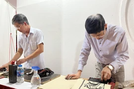 Thực hiện công đoạn in tranh trên giấy Dó. (Ảnh: Minh Ngọc/TTXVN phát)