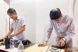 Thực hiện công đoạn in tranh trên giấy Dó. (Ảnh: Minh Ngọc/TTXVN phát)