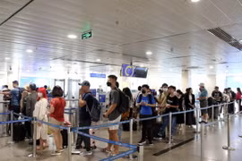 Hành khách xếp hàng vào khu vực soi chiếu kiểm tra an ninh. (Ảnh: Tiến Lực/TTXVN)