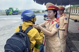 Cảnh sát Giao thông cấp phát mũ bảo hiểm đạt chuẩn cho người dân. (Ảnh: TTXVN phát)