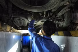 Kiểm định viên kiểm tra gầm bệ phương tiện giao thông. (Ảnh: Tuấn Anh/TTXVN)