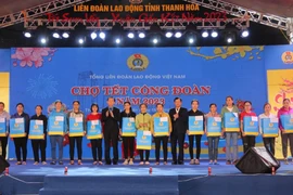 Ông Võ Mạnh Sơn (thứ 7, trái sang), Chủ tịch Liên đoàn Lao động tỉnh Thanh Hóa trao quà cho công nhân có hoàn cảnh khó khăn tại chương trình. (Ảnh: Khiếu Tư/TTXVN)