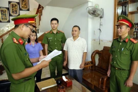 Cán bộ điều tra tống đạt quyết định khởi tố, thi hành lệnh bắt Lê Tự Trị, Giám đốc Trung tâm đăng kiểm xe cơ giới 85-02D, ở nhà riêng tại phường Phú Lâm, thành phố Tuy Hòa, tỉnh Phú Yên. (Ảnh: TTXVN phát) 