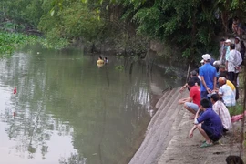 Lực lượng chức năng tìm kiếm thi thể cháu bé bị đuối nước. (Ảnh: Nhựt An/TTXVN)