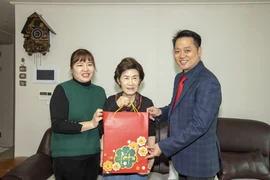 Đại biện lâm thời Nguyễn Việt Anh (phải) tặng quà Tết cho gia đình chị Nga. (Ảnh: Anh Nguyên/TTXVN)