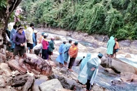 Các lực lượng chức năng đang phối hợp với người dân địa phương tổ chức tìm kiếm em D. (Ảnh: Trịnh Bang Nhiệm/TTXVN)