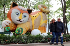 Du khách quốc tế hứng thú chụp ảnh cùng hình tượng mèo, linh vật năm Quý Mão 2023 bên hồ Gươm. (Ảnh: Thanh Tùng/TTXVN) 