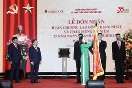 Phó Chủ tịch nước Võ Thị Ánh Xuân gắn Huân chương Lao động hạng Nhất lên lá cờ truyền thống của Ngân hàng Nông nghiệp và Phát triển nông thôn. (Ảnh: Lâm Khánh/TTXVN)