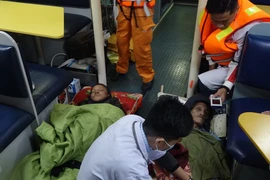 Hai bệnh nhân được hỗ trợ y tế trên tàu SAR 412 trước khi chuyển về bờ. (Ảnh: TTXVN phát)