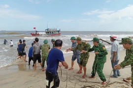 Bộ đội Biên phòng tỉnh Quảng Trị hỗ trợ ngư dân cố định tàu cá mắc cạn. (Ảnh: TTXVN phát) 