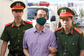 Lực lượng chức năng dẫn giải bị cáo Tô Anh Dũng, cựu Thứ trưởng Bộ Ngoại giao, tới phiên tòa xét xử. (Ảnh: Phạm Kiên/TTXVN) 