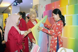 Đại diện các cơ quan ngoại giao trên địa bàn Thành phố Hồ Chí Minh tham quan khu trưng bày sản phẩm lụa may áo dài. (Ảnh: Mỹ Phương/TTXVN)