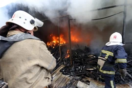 Lính cứu hỏa dập lửa đám cháy khu chợ ở Donetsk sau vụ pháo kích. (Nguồn: AFP/TTXVN)