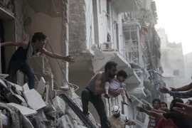 Nhân viên cứu hộ chuyển em bé ra khỏi tòa nhà đổ nát sau các cuộc không kích tại thành phố Aleppo. (Nguồn: AFP/TTXVN)