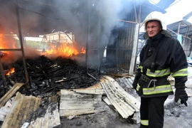 Lính cứu hỏa dập lửa đám cháy khu chợ ở Donetsk sau vụ pháo kích. (Nguồn: AFP/ TTXVN)