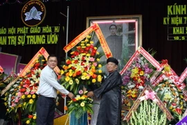 Phó Chủ tịch tỉnh An Giang Võ Anh Kiệt (áo trắng) tặng hoa chúc mừng đại diện Ban Trị sự Trung ương Giáo hội Phật giáo Hòa Hảo nhân kỷ niệm 75 năm Ngày khai sáng đạo Phật giáo Hòa Hảo. (Ảnh: Công Mạo/TTXVN)