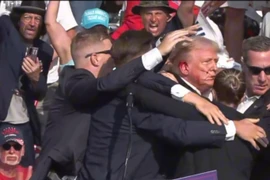 Cựu Tổng thống Donald Trump được mật vụ Mỹ hộ tống rời khỏi bục diễn thuyết trong cuộc vận động tranh cử ở thành phố Butler, bang Pennsylvania sau khi xảy ra vụ nổ súng. (Ảnh: THX/TTXVN)