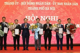 Bí thư Thành ủy Vương Đình Huệ và Chủ tịch UBND thành phố Chu Ngọc Anh trao quyết định và tặng hoa chúc mừng năm tân Phó Chủ tịch UBND thành phố Hà Nội. (Ảnh: Văn Điệp/TTXVN)