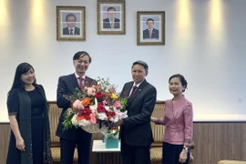 Đại sứ Nguyễn Tất Thành tặng hoa chúc mừng Đại sứ Lào Sisavath Inphachanh. (Ảnh: Nguyễn Minh/Vietnam+)