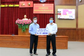 Đại diện Đài Phát thanh-Truyền hình Vĩnh Long trao bảng ủng hộ 3 tỷ đồng. (Ảnh: Phạm Minh Tuấn/TTXVN)
