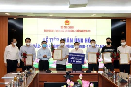 Bộ trưởng Bộ Tài chính Hồ Đức Phớc (thứ 3, từ trái sang) cùng các tổ chức tham gia ủng hộ Quỹ vaccine phòng, chống COVID-19. (Ảnh: Phạm Hậu/TTXVN)