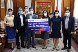 Ông Nguyễn Đức Vũ (Trái) Tổng Giám đốc Ngân hàng Liên doanh Lào - Việt đang trao tượng trưng số tiền 50.000.000 kip (Khoảng 115 triệu đồng) ủng hộ Quỹ vaccine phòng chống COVID-19 của Việt Nam cho Công sứ Trịnh Minh Tâm. (Ảnh: Phạm Kiên/TTXVN)