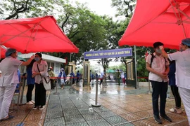 Đo thân nhiệt, sát khuẩn tay cho thí sinh trước khi vào phòng thi tại điểm thi trường THPT Trần Nhân Tông. (Ảnh: Thanh Tùng/TTXVN)