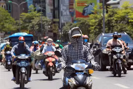 Người dân đi trên đường phải bịt kín để bảo vệ cơ thể dưới cái nắng trên 40 độ C. (Ảnh: Phan Tuấn Anh/TTXVN)
