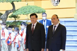 Chủ tịch nước Nguyễn Xuân Phúc và Tổng Bí thư, Chủ tịch nước CHDCND Lào Thongloun Sisoulith nghe Quân nhạc cử Quốc thiều hai nước tại lễ đón. (Ảnh: Lâm Khánh/TTXVN)