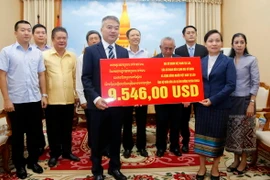 Sứ quán Việt Nam trao tiền ủng hộ cho người dân bị thiên tai của Lào. (Ảnh: Phạm Kiên/Vietnam+)