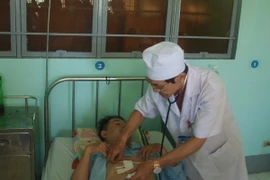 Bác sỹ của Trung tâm y tế huyện Nhơn Trạch khám lại vết thương cho bệnh nhân P.T.T. (Ảnh: Lê Xuân/TTXVN)