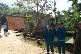 Lực lượng dân quân xã Hạ Bì canh gác không cho người dân đi vào vùng sạt lở nguy hiểm. (Ảnh: Nhan Sinh/TTXVN)